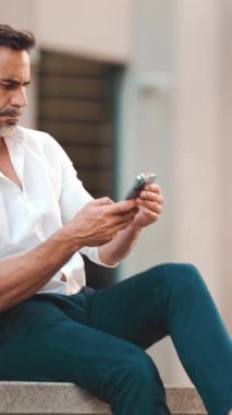 Sakallı, olgun bir iş adamı şehrin finans bölgesinde bankta cep telefonu kullanıyor. Başarılı adam akıllı telefondan bilgi aktarıyor. Kamera yakınlaştır