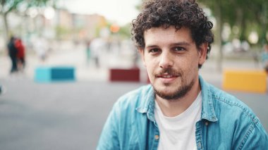  Kot gömlekli genç sakallı adamın yakın plan portresi modern şehir arka planında kameraya poz verip gülümsüyor..