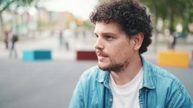  Kot gömlekli genç sakallı adamın yakın plan portresi modern şehir arka planında kameraya poz verip gülümsüyor..