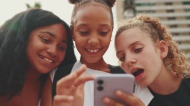 Gençlik öncesi üç kız arkadaş rıhtımda cep telefonu kullanarak oturuyorlar, video izliyorlar, fotoğraf çekiyorlar. Gençler şehir planında şehir dışında geziyorlar.
