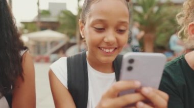 Genç kız rıhtımda otururken cep telefonu kullanıyor. Genç kız akıllı telefondan mobil oyunlar oynuyor.