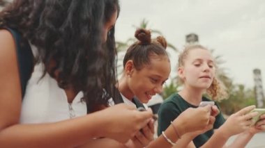 Gençlik öncesi üç kız arkadaş rıhtımda cep telefonuyla oturuyorlar. Kentin arka planında, açık havada akıllı bir telefonla oyun oynayan üç genç.