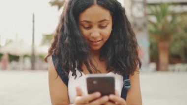 Genç kız rıhtımda otururken cep telefonu kullanıyor. Genç kız akıllı telefondan video görüşmesi yapıyor.