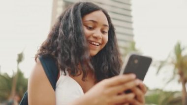 Genç kız rıhtımda otururken cep telefonu kullanıyor. Genç kız akıllı telefondan video görüşmesi yapıyor.