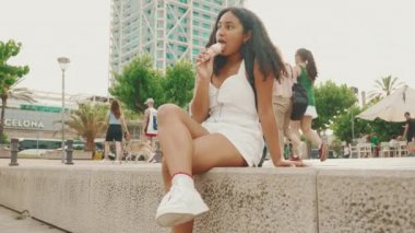 Ergenlik öncesi kız, iskelede bacakları sallanarak oturarak dondurma yemekten hoşlanır.