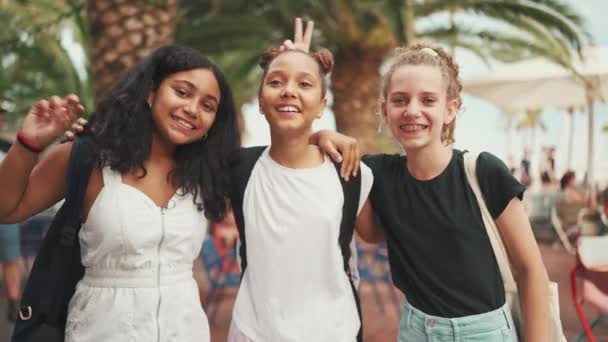 三个十几岁前的女朋友站在街上笑着 互相拥抱 在镜头前做鬼脸 三个在城市景观背景下的户外青少年 — 图库视频影像