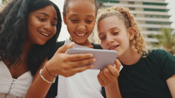 Trzy Nastoletnie Koleżanki Siedzą Nabrzeżu Używając Telefonu Komórkowego Oglądając Filmy — Zdjęcie stockowe