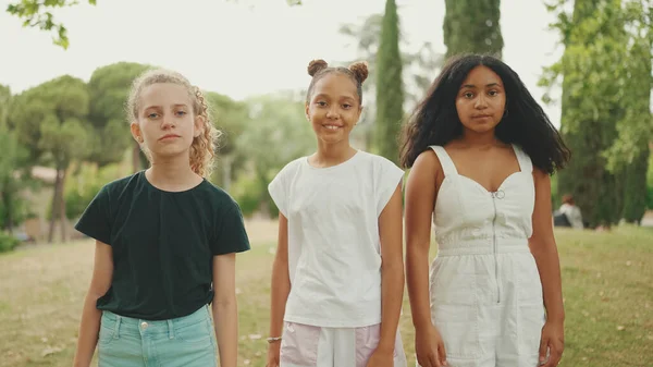 Smiling three girls friends pre-teenage cross their arms in dance move in the park