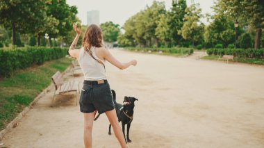 Kız arka köpekle parkta yürüyor..
