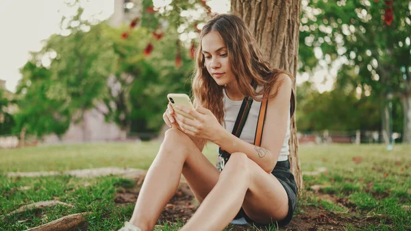 Krásná Dívka Dlouhými Vlnitými Vlasy Bílém Top Používá Mobilní Telefon — Stock fotografie