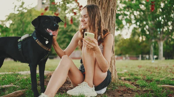 Cute Girl Czarnym Psem Spoczywa Pod Drzewem Trawniku Szczęśliwy Pies — Zdjęcie stockowe