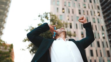 Ofis kıyafetleri içinde sakallı orta yaşlı bir işadamı cep telefonu kullanıyor. Başarılı bir adam duygusal olarak akıllı telefondan konuşuyor. Haberler iyi.