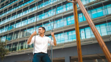Sakallı, beyaz tişörtlü, salıncaklı ve salıncakta sallanan olgun bir iş adamı. Başarılı adam yorucu bir günün ardından dinleniyor.