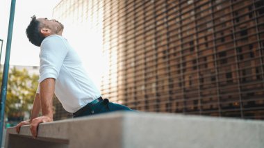 Beyaz gömlek giyen, sakallı, olgun bir iş adamı modern şehrin sokaklarında bankta oturuyor. Başarılı adam dinleniyor.