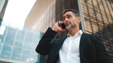 Ofis kıyafetleri içinde sakallı orta yaşlı bir işadamı cep telefonu kullanıyor. Başarılı bir adam duygusal olarak akıllı telefondan konuşuyor. Hayal kırıklığı, sorun.