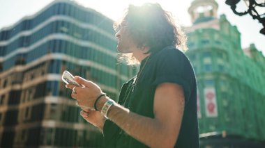 Uzun kıvırcık saçlı ve sakallı çekici İtalyan çocuk cep telefonu kullanıyor. Güneş gözlüklü şık bir adam akıllı telefonundaki haritayla yerini belirliyor.