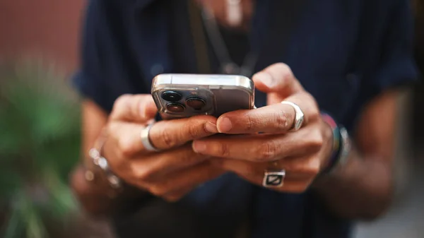 Close-up of male hands in bracelets and rings. Man is using mobile phone. Guy writes message on his smartphone