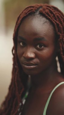 Afrikalı örgüleri olan ve kameraya bakan muhteşem bir kadının yakın çekimi.
