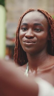 Sokakta üzerinde Afrika örgüsü olan gülümseyen muhteşem bir kadın duruyor ve cep telefonu kullanıyor. Şık bir kız selfie çekiyor.