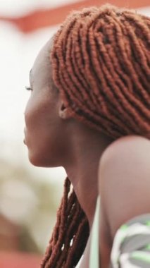 Clouse-up, Afrika örgülü muhteşem kadın köprüde üstte ayakta duruyor.