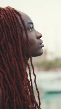 Deniz manzaralı Afrika örgülü muhteşem bir kadının profilinin yakın plan çekimleri.