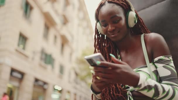 Великолепная Женщина Африканскими Косичками Верхней Части Сидит Наушниками Улице Использует — стоковое видео