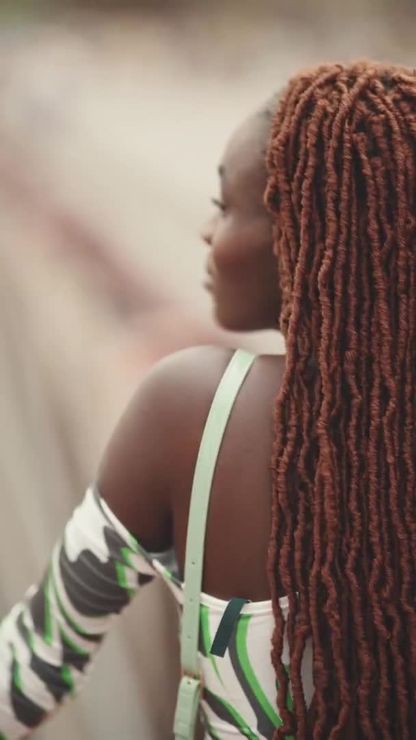 垂直视频 漂亮的女人 戴着非洲辫子 头顶站在桥上的背景高速公路上 古板的女孩转过头 看着摄像机 焦虑症背景 — 图库视频影像