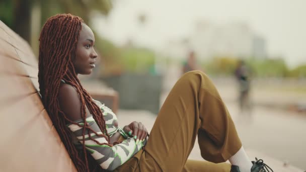 穿着非洲辫子 裤子的漂亮女人坐在长椅上 — 图库视频影像