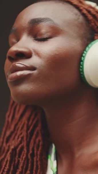 Vertical Video 在街上欣赏音乐的戴着非洲辫子的漂亮女人的特写 一个时髦的女孩闭着眼睛听音乐 — 图库视频影像