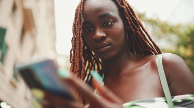Üstü başı Afrika örgülü muhteşem bir kadın sokakta dikiliyor ve cep telefonu kullanıyor. Şık kız akıllı telefondan mesaj yazıyor.