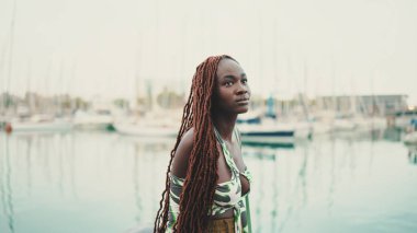 Afrika örgülü bir kadın limandaki yat ve gemilere bakıyor.. 