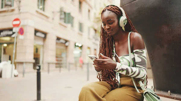Gyönyörű Afrikai Fonatokkal Felső Ülésekkel Fejhallgatóval Utcán Mobiltelefont Használ Stílusos — Stock Fotó