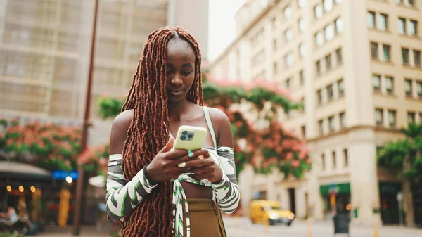 Улыбающаяся Красотка Африканскими Косичками Верхней Части Стоит Улице Пользуется Мобильным — стоковое фото