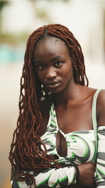 Close up portrait of gorgeous woman with African braids wearing walks down the street.