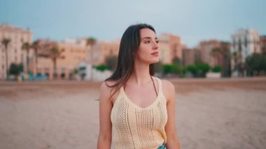 Kumsalda uzun saçlı güzel kahverengi saçlı kadın yürüyor ve etrafına bakıyor. Uzun kirpikleri olan güzel bir kız. Yavaş çekim
