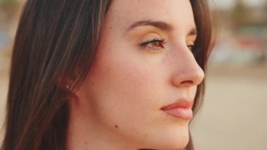 Uzun saçlı, güzel, kahverengi saçlı bir kadın profili. Uzun kirpikleri ve çilleri olan güzel bir kız. yavaş çekim