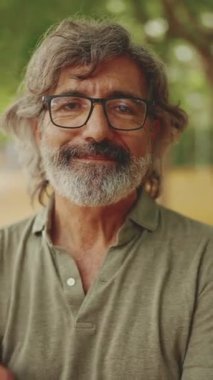 Görüntü: Clouse-up, gri saçlı ve sakallı orta yaşlı dost canlısı bir adam kameraya bakıyor. Gözlüklü olgun beyefendi kameraya gülümsüyor.