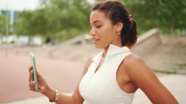 Beyaz saçlı, bronzlaşmış, at kuyruklu güzel kadın cep telefonu kullanıyor. Kız akıllı telefon kullanarak görüntülü arama yapıyor.