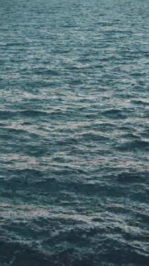VERTICAL VIDEO: Sun glare on the water. Natural background with sun glints on surface of water. Never endless sea water surface view and sun blaze. Texture of water surface of sea reflection of sun's rays