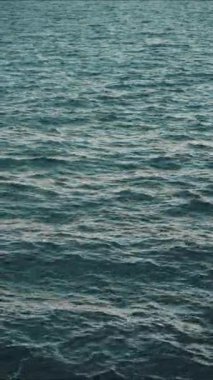 VERTICAL VIDEO: Sun glare on the water. Natural background with sun glints on surface of water. Never endless sea water surface view and sun blaze. Texture of water surface of sea reflection of sun's rays