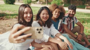 Çok ırklı gençler yaz günü dışarıda selfie çekmeyi düşünüyorlar. Bir grup gülen arkadaş akıllı telefon kamerasına poz veriyor.