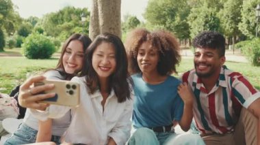 Çok ırklı gençler yaz günü dışarıda selfie çekmeyi düşünüyorlar. Bir grup gülen arkadaş akıllı telefon kamerasına poz veriyor.