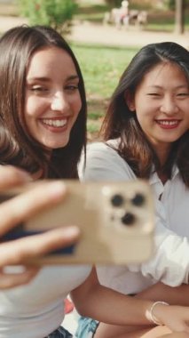 Mutlu çoklu etnik kökenli gençler yaz günü açık havada selfie çekmeyi düşünüyorlar. Bir grup gülen arkadaş akıllı telefon kamerasına poz veriyor.