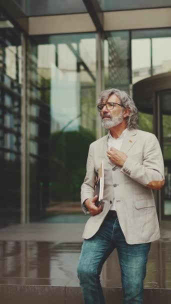 Vertical Video Mature Businessman Beard Glasses Wearing Gray Jacket Holding — Vídeo de stock