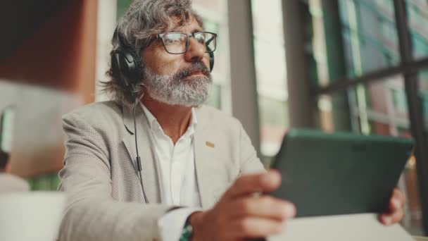 Gözlüklü Kulaklıklı Olgun Bir Adamı Açık Bir Kafede Oturup Tablet — Stok video