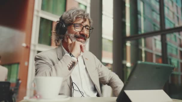 Mature Businessman Beard Eyeglasses Headphones Sits Outdoor Cafe Works Using — Vídeo de stock