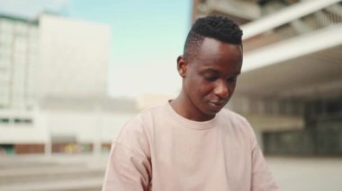 Üniversitenin dışında oturan Afrikalı genç bir öğrenci, cep telefonu kullanıyor, sesli mesaj gönderiyor.