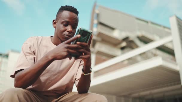 Pemuda Afrika Duduk Luar Universitas Menggunakan Ponsel Ketukan Pada Layar — Stok Video