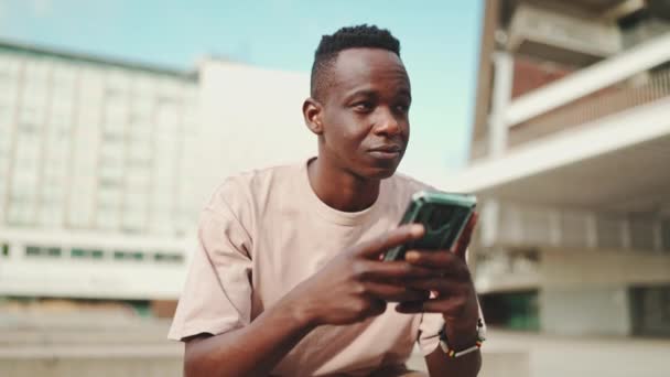 Mladý Africký Student Sedí Mimo Univerzitu Používá Mobilní Telefon Odposlechy — Stock video