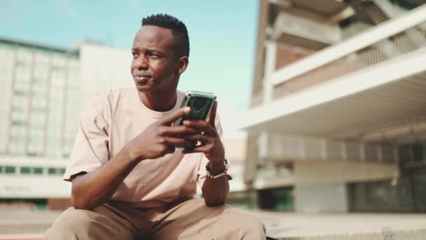 Mladý Africký Student Sedí Mimo Univerzitu Používá Mobilní Telefon Odposlechy — Stock video
